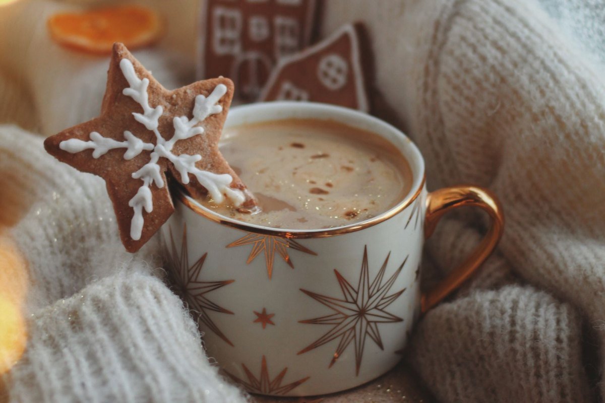 Gingerbread latte in a gold rimmed mug with star cookies and a cozy knit sweater