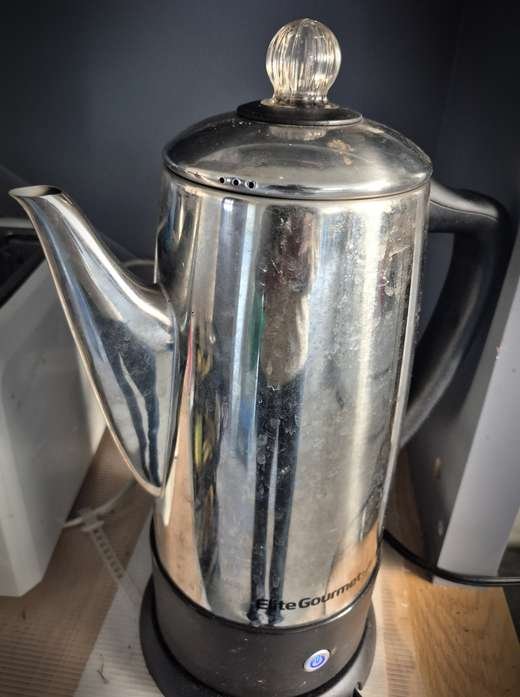 Stainless steel electric coffee percolator on a kitchen shelf